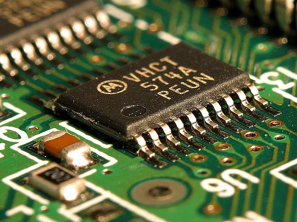 Close-up of a semiconductor chip and metallic connections on a green circuit board